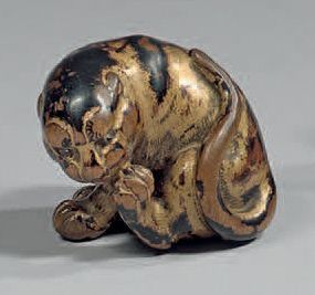 JAPON Netsuke en bois laqué d'or, représentant un tigre assis léchant sa patte. Signé...
