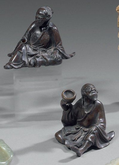 null Deux petites statuettes de personnages assis en bronze à patine brune, l'un...