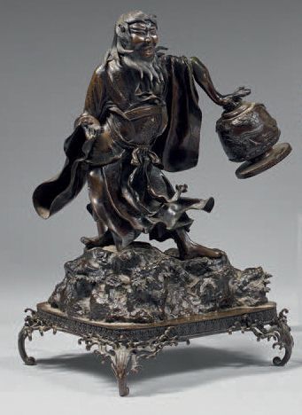 JAPON Okimono en bronze à patine brune, aïnu debout sur un rocher, soulevant un vase...