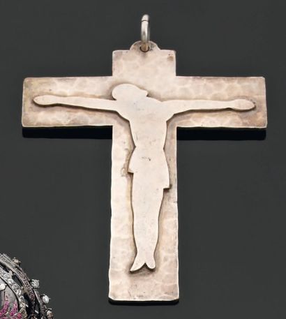 JEAN DESPRES Pendentif en métal argenté martelé, stylisant le Christ en croix. Signé....
