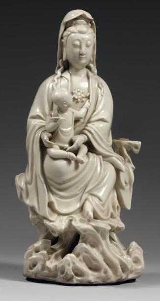 CHINE Figurine représentant la déesse kwan-hin émaillée en blanc assise sur un rocher...