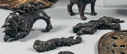 JAPON Trois ornements en bronze à patine brune et traces de dorure en forme de shishi...