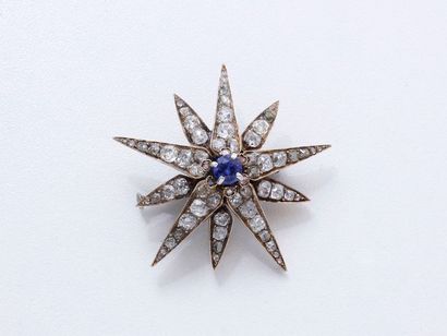 null Broche en or 750 millièmes stylisant une étoile centrée d'une pierre bleue entouré...