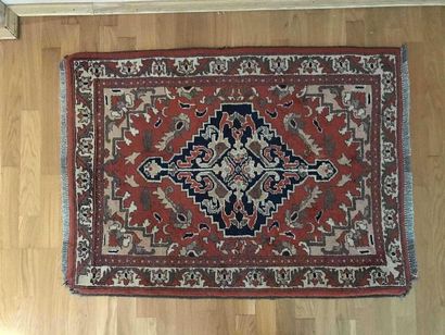 null Woollen rug decorated with a stylised central medallion on a red background....