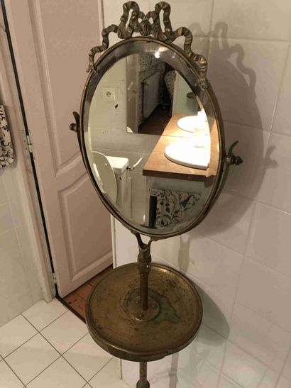 null Mirror on foot in gilded metal.

The oval mirror rests on a circular shelf supported...