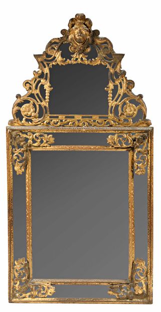 null 
Important miroir à parecloses en bois doré à décor de feuillage et mascaron....