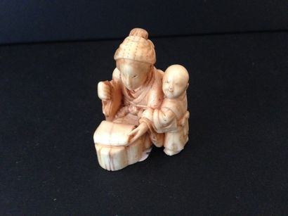 null Netsuke. Personnage assis avec son enfant en ivoire sculpté. Japon. XIXème siècle....