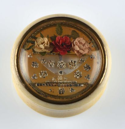 null Tabatière ronde en ivoire à décor floral en perles et textile sous verre. XIXe...