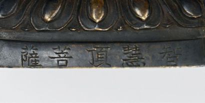 CHINE - TIBET Bouddha en bronze à patine brune et traces de dorure.
Inscriptions...