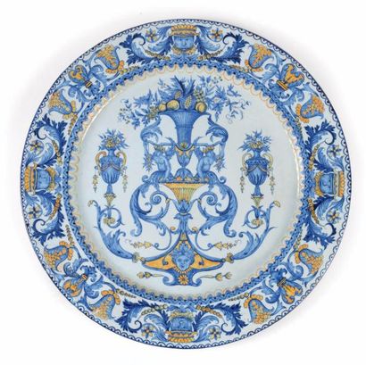 ITALIE Grand plat rond en faïence à décor en camaïeu bleu et orangé de vases fleuris...