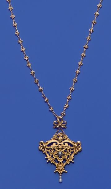 null Chaîne en or (750/1000e) et un pendentif en métal doré à décor ajouré de volutes...