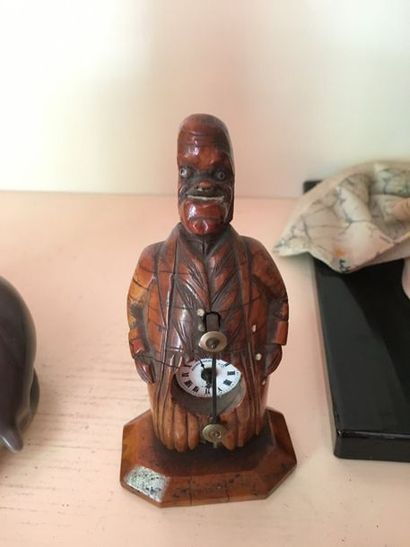 null Une petite horloge en bois sculptée à décor d'un homme caricaturé, cadran signé...