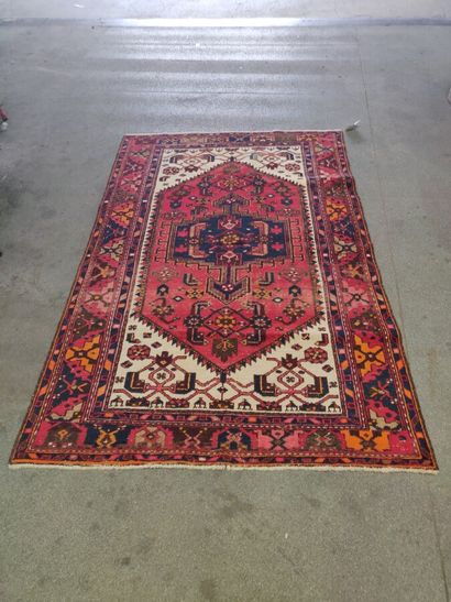 null Oriental carpet with a central blue medallion on a red background. Wear and...
