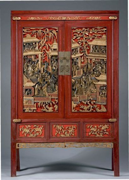 CHINE Armoire en bois laqué rouge à décor polychrome et or en bas-relief de scènes...