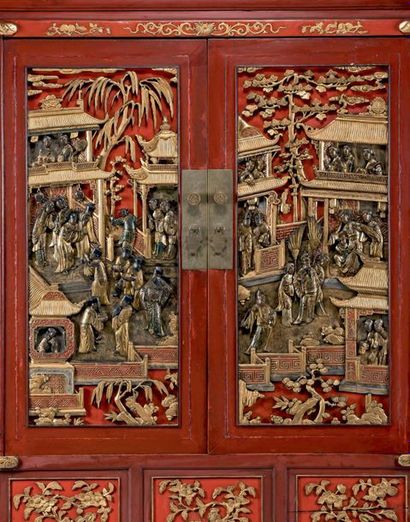 CHINE Armoire en bois laqué rouge à décor polychrome et or en bas-relief de scènes...