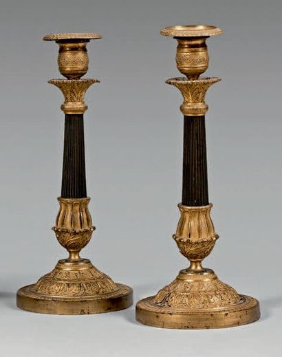 null Pair of candlesticks in patinated and gilt bronze. Fluted barrel. Capital decorated...