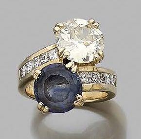 null A "you and me" ring set with a round half-cut diamond and a round sapphire,...