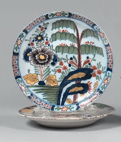 DELFT Two plates with polychrome decoration of flowers, shrubs and flowered fence...