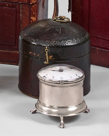 null Small cylindrical silver table clock with three claw feet. Cock movement signed...
