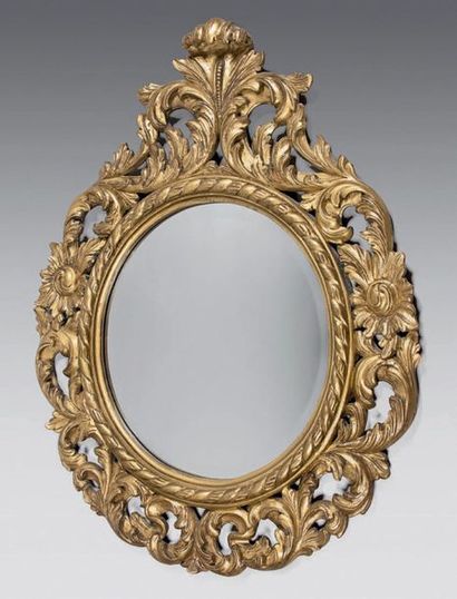 Round bevelled mirror in a giltwood pediment...