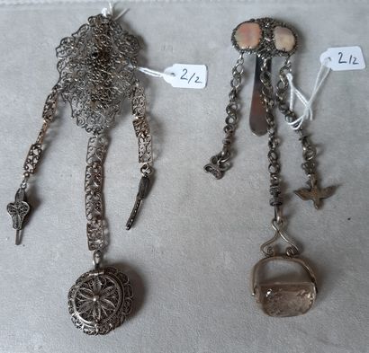 null Two silver chatelaines, one with filigree decoration, holding a bellows, a stylized...