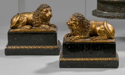 null Two gilded plaster statuettes of reclining lions on painted bases in simulated...