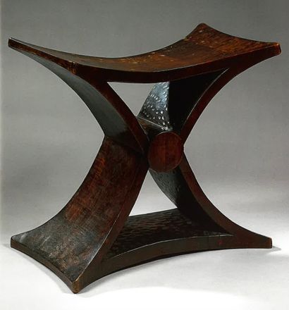 Marcel COARD (1889-1975), Tabouret de style Africain en forme de X en bois naturel patiné entièrement taillé à partie centrale par un cylindre, base légèrement convexe