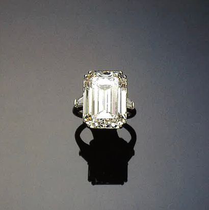 BAGUE signée Harry WINSTON en platine sertie d'un important diamant de taille émeraude à pans coupés taillé à degrés entre deux diamants trapèzes