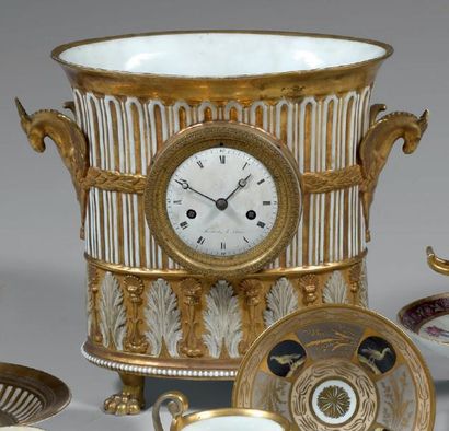 PARIS Pendule en porcelaine, formée d'un vase tripode ovale orné de godrons, de feuilles...