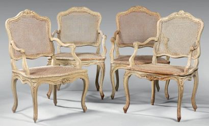  Quatre fauteuils cannés à dossier plat en hêtre laqué crème mouluré sculpté de fleurettes....