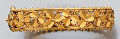 null Bracelet large rigide ouvrant en or jaune ajouré et décor de trèfles. Vers 1900....