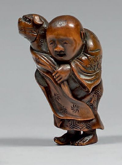 JAPON - Époque EDO (1603-1868) Netsuke en buis, enfant debout tenant une marionnette...