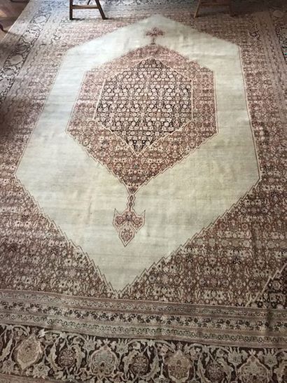 null 
Grand tapis persan orné d'un médaillon central sur fond beige, bordures à 6...