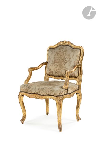 null A giltwood armchair with a flat back and foliage and flowers decoration, resting...