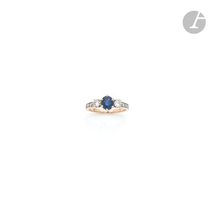 null An 18K (750 ‰) gold ring, set with an oval-shaped sapphire shouldered with round...