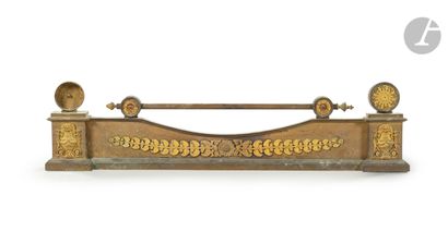  A patinated and gilded bronze fire-bar, decorated with a vase of flowers, a frieze...