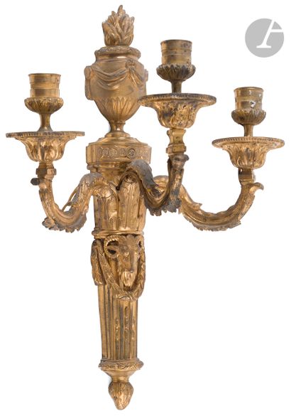null A pair of ormolu three-light sconces decorated with a vase and a ram's head;...