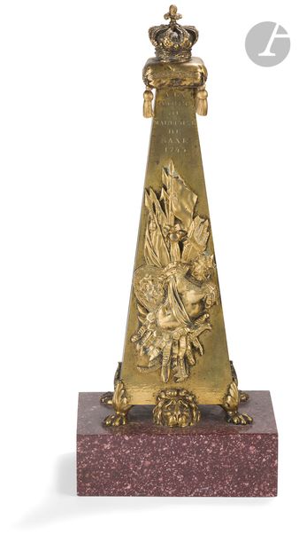  Obélisque en COMPOSITE A PARTIR D'UN OBELISQUE EXISTANT,  doré à décor d’un trophée...