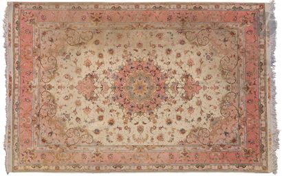 null Tabriz. Wool and silk carpet decorated with an old pink medallion on an ivory...