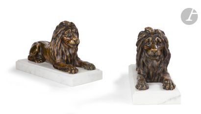 null A pair of bronze lion figures with brown patina; (on white marble bases brought...