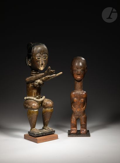 null A group of two female statuettes with ringed necks, one with half-closed eyes...