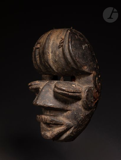 null A beautiful and very old mask with a double look, its mouth open, its slightly...