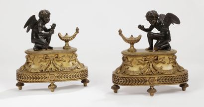 null Paire de chenets en bronze patiné et doré à décor d'amours se chauffant à une...