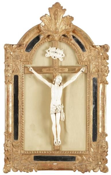 null Crucifix en ivoire sculpté, dans un cadre en bois redoré cintré à parecloses...