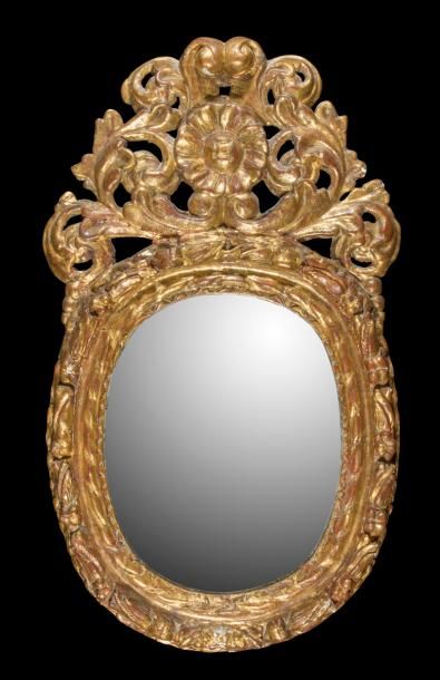 null Miroir en bois doré de forme ovale surmonté d’un fronton ajouré à feuillages...