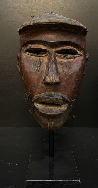 ANONYME. "Bakongo面具"（约1920年）。安装在黑色金属底座上的木质雕塑。尺寸：31.5 x 13 x 10厘米。代表白人的面具，比利时铁路建设期间的工头。尽管在非西方社会的形象艺术中，对旅行者、商人、士兵和其他欧洲传教士的表现比比皆是，但对他们的研究却很少。然而，早在1937年，德国人类学家朱利叶斯-利普斯（Julius...