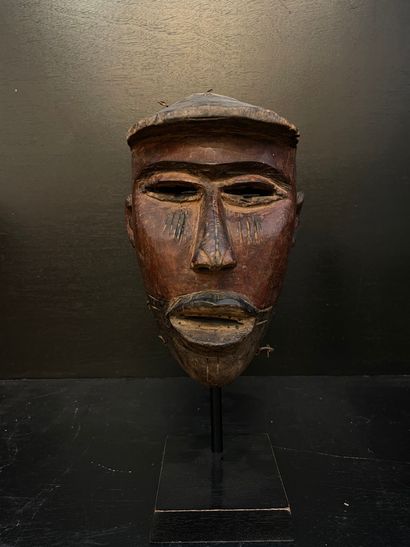 ANONYME. "Bakongo面具"（约1920年）。安装在黑色金属底座上的木质雕塑。尺寸：31.5 x 13 x 10厘米。代表白人的面具，比利时铁路建设期间的工头。尽管在非西方社会的形象艺术中，对旅行者、商人、士兵和其他欧洲传教士的表现比比皆是，但对他们的研究却很少。然而，早在1937年，德国人类学家朱利叶斯-利普斯（Julius...
