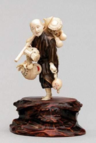null OKIMONO en ivoire et bronze représentant un colporteur portant des tambours...