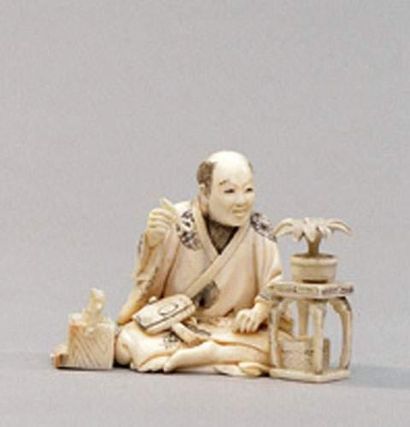 null OKIMONO en ivoire représentant un homme assis s'apprêtant à tailler un bonsaï.
Japon,...