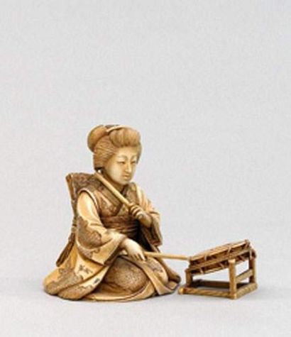 null OKIMONO en ivoire teinté représentant une geisha assise jouant du tambour posé...